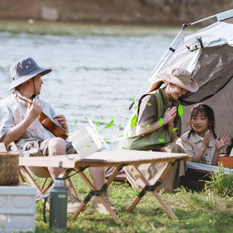 Camping Flashlight - Light placed on a folding camp table at a lakeside campsite with a family gathered nearby