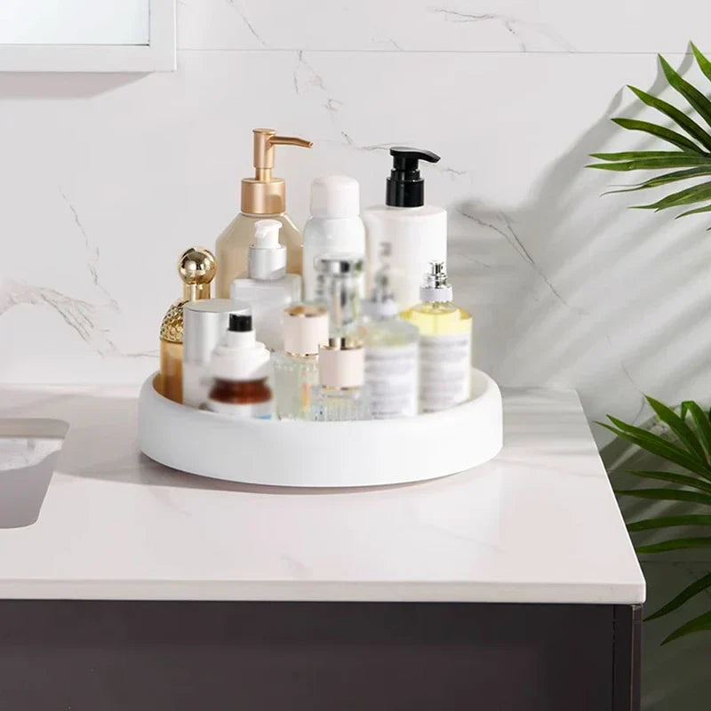 Rotating Storage Turntable Tray Organizer - White round tray holding assorted skincare and perfume bottles, placed on a bathroom countertop