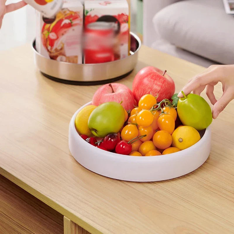 Rotating Storage Turntable Tray Organizer - White rotating tray holding fruit on a light wooden table, with a hand placing a green fruit onto the tray