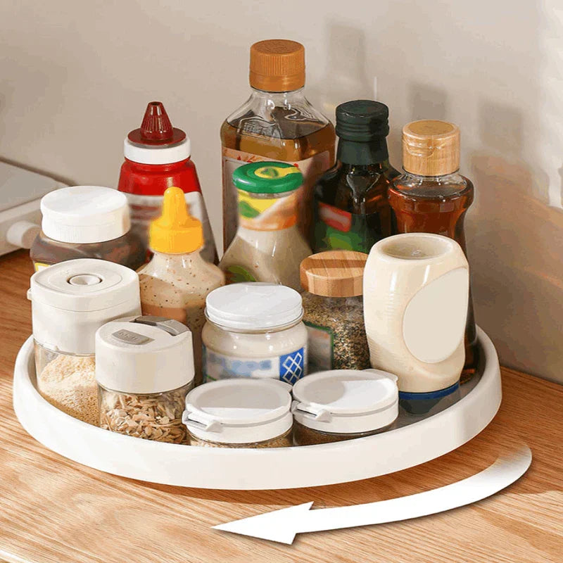Rotating Storage Turntable Tray Organizer - White rotating tray holding assorted cooking condiments and spice containers, with a rotation arrow visible