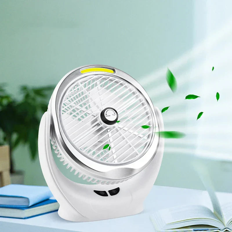 Desk Fan - White desktop fan blowing wind on a table with stacked blue books and an open book, green leaves in the breeze