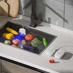 Ultrasonic Cleaner Machine - One small white wired electronic device placed in a water-filled kitchen sink with produce, two identical devices resting on the adjacent countertop