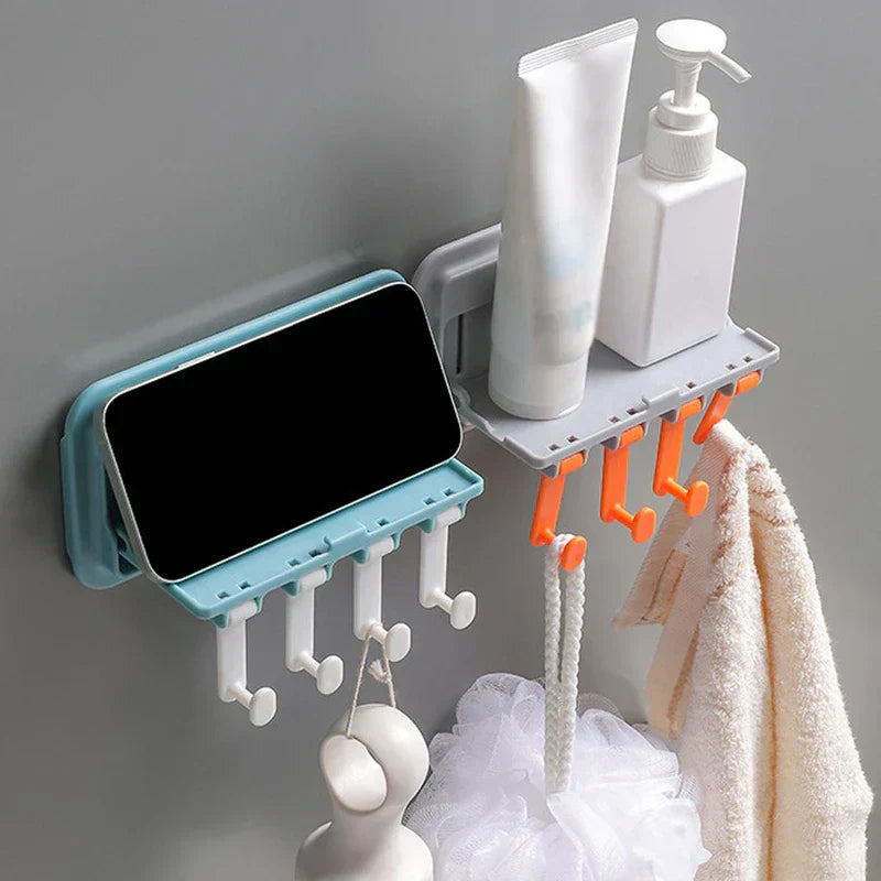 Utility Hook Hanger - Two adjacent wall-mounted holders: a light blue phone stand with white hooks, and a gray shelf with orange hooks holding toiletries, a loofah, and a towel