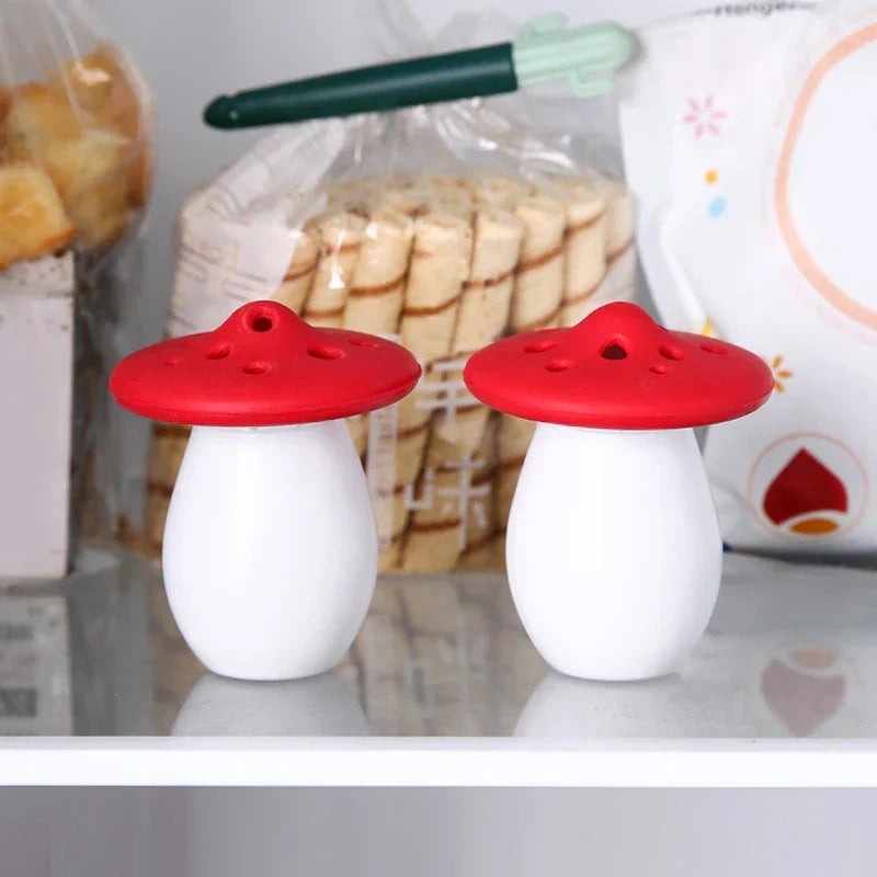 Mini Fridge And Wine Cooler - Two mushroom-shaped containers with white bases and red perforated lids sit on a clear glass refrigerator shelf, with packaged food behind them.