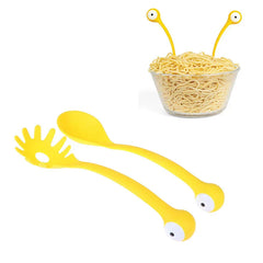 Soup Ladle - Yellow serving utensils shown next to a glass bowl of cooked noodles with utensil eye stalks peeking above the noodle line