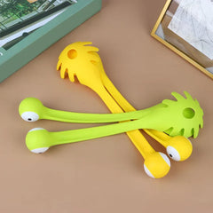 Soup Ladle - Crossed yellow and lime green pasta forks with eye-detailed handle ends, placed on a flat surface.
