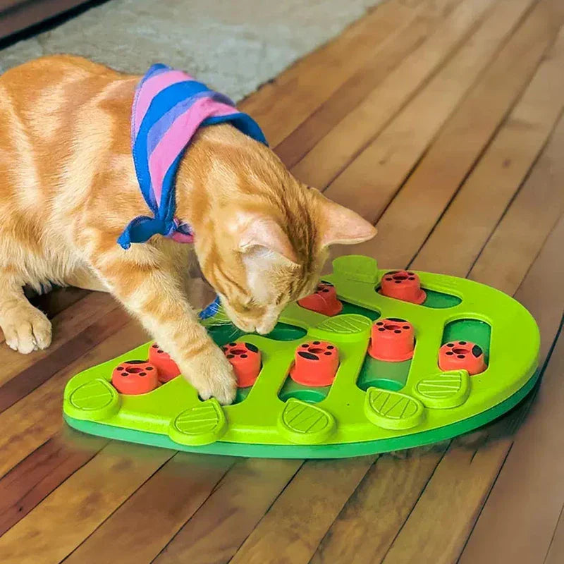 Cat Slow Feeder - Orange tabby cat wearing a striped bandana interacting with the green leaf-shaped feeding dish on a wood floor