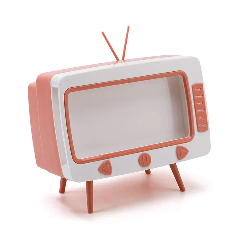 Coral and white retro TV-shaped novelty tissue dispenser with antennae, control buttons, and legs, on a plain white background