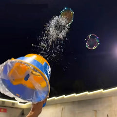 Bubble Gun - Hand holding a blue and yellow bubble toy pointing upward, releasing bubbles and spray against a dark night sky, near a lit building edge.