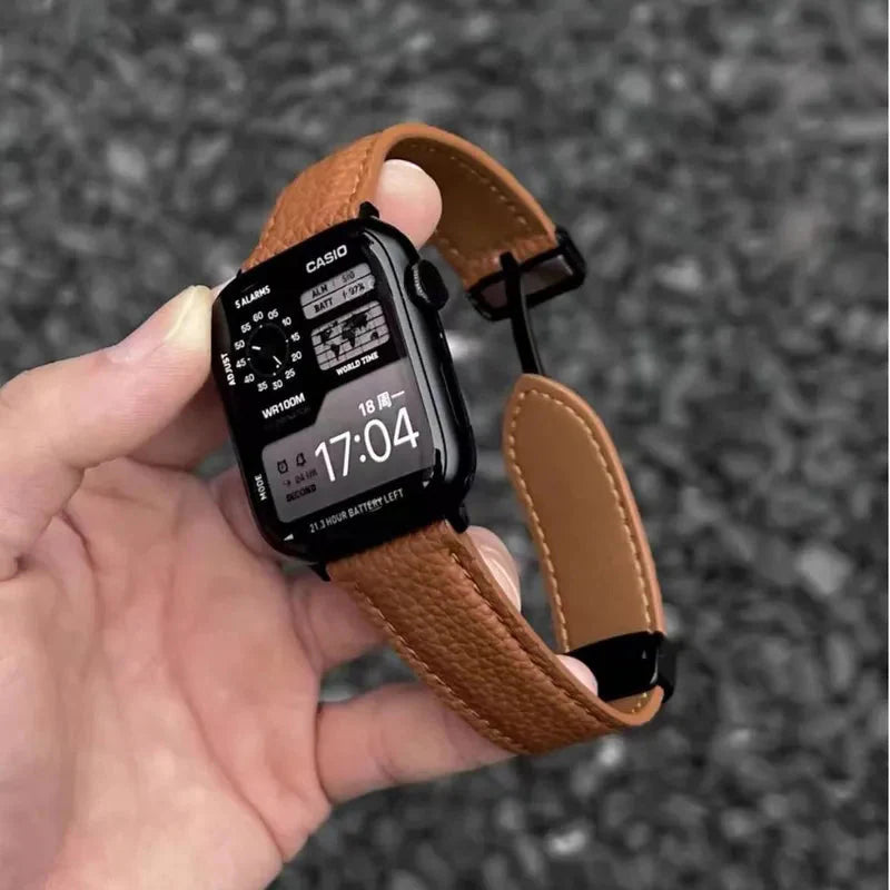Apple Watch Band - Hand holds a smartwatch with tan pebbled leather band, watch face shows Casio branding and 17:04 time
