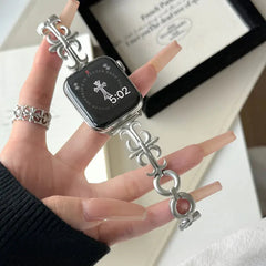Silver gothic cross link apple watch band attached to a silver Apple Watch, held on a hand with matching cross ring