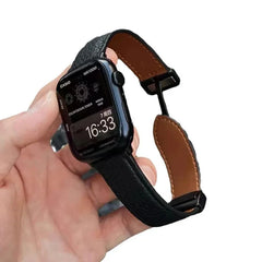 Apple Watch Band - black pebbled leather strap with tan lining held in hand against white background
