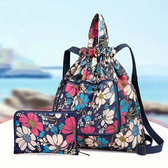 Travel Backpack - Foldable floral backpack with matching pouch displayed against a blurred seaside background