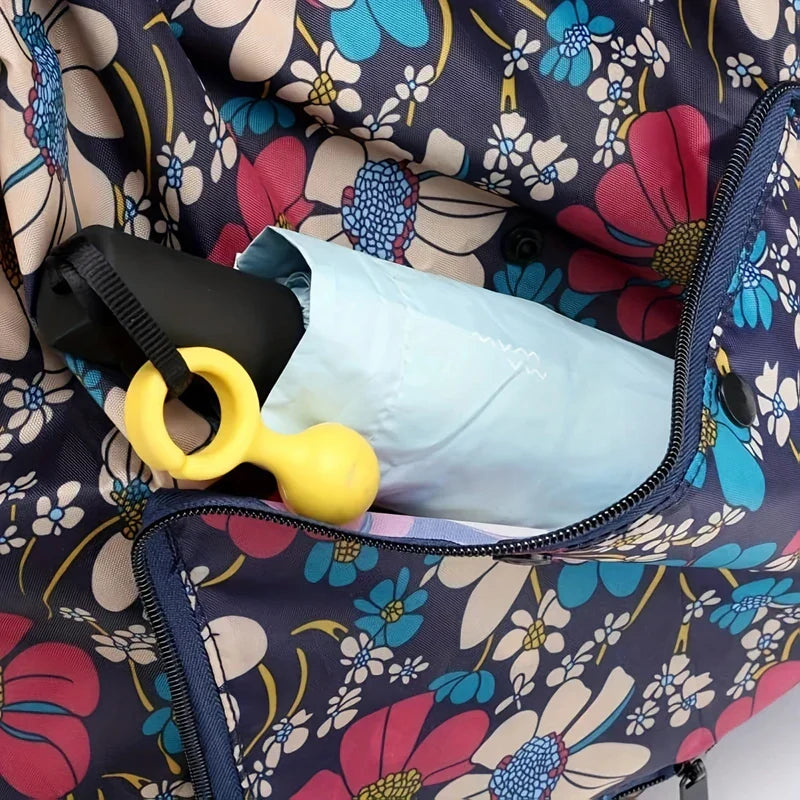 Travel Backpack - Close-up of a zippered pocket on the dark floral backpack holding a folded umbrella and yellow handled item.
