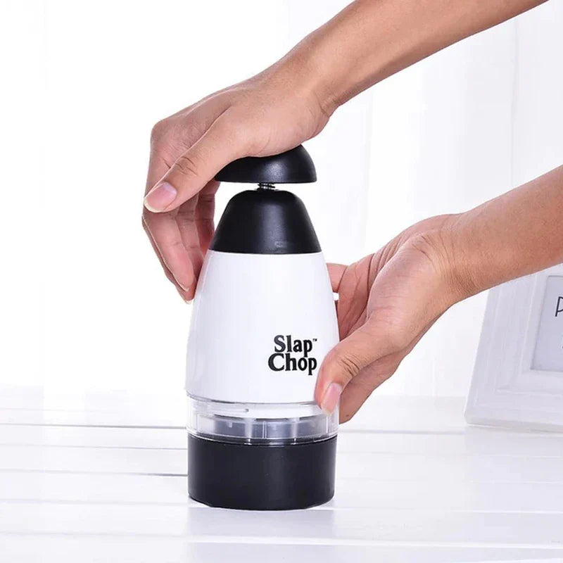Garlic Mincer - Two hands hold and operate the manual food chopper resting on a light-colored flat surface.