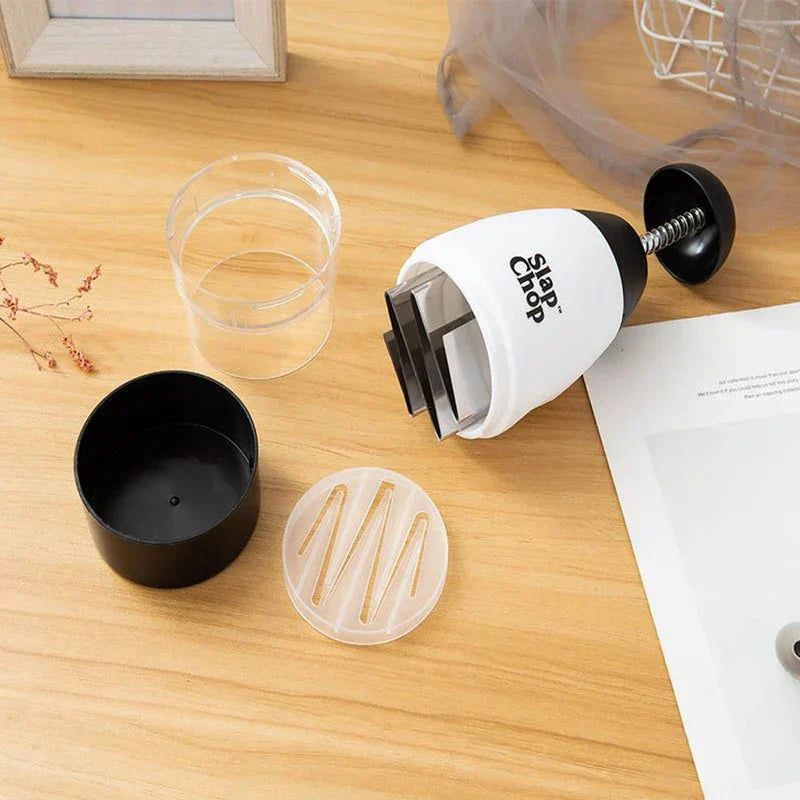 Garlic Mincer - Slap Chop chopper disassembled with its clear plastic cup, black container, and clear lid laid out on a light wooden surface.