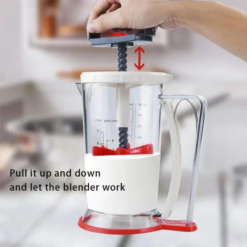 Pancake Batter Dispenser - Hand pulling the top plunger of the batter dispenser up and down, with red mixing blades visible inside the container.