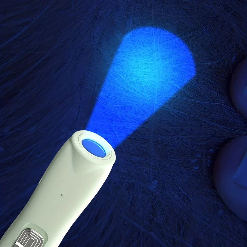 A light-colored hair trimmer emits a bright blue beam onto a dark, textured surface with fine light strands.