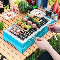 People using a teal disposable grill with a grill grate to cook shrimp, veggie, and meat skewers on an outdoor picnic table