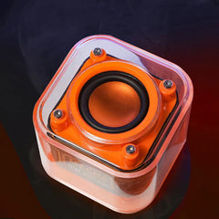 Top-down view of a clear and orange portable bluetooth speaker showing its speaker driver and four corner screws against a dark red-black background.