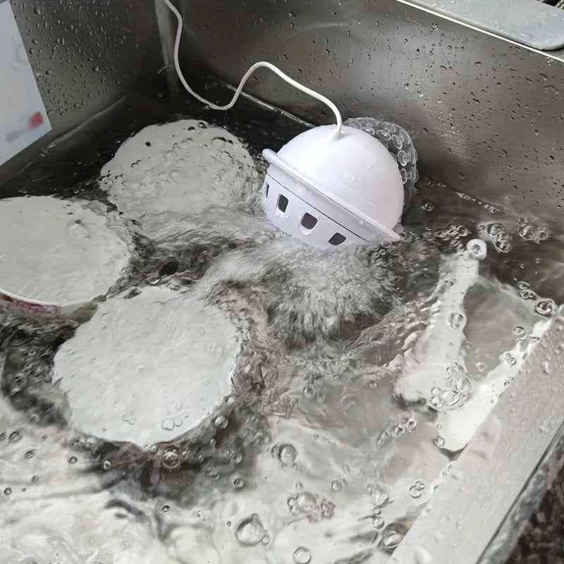 Mini-Spülmaschine in Betrieb in einem Edelstahlspülbecken mit Seifenwasser und Geschirr darin