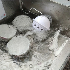 Mini-Spülmaschine in Betrieb in einem Edelstahlspülbecken mit Seifenwasser und Geschirr darin