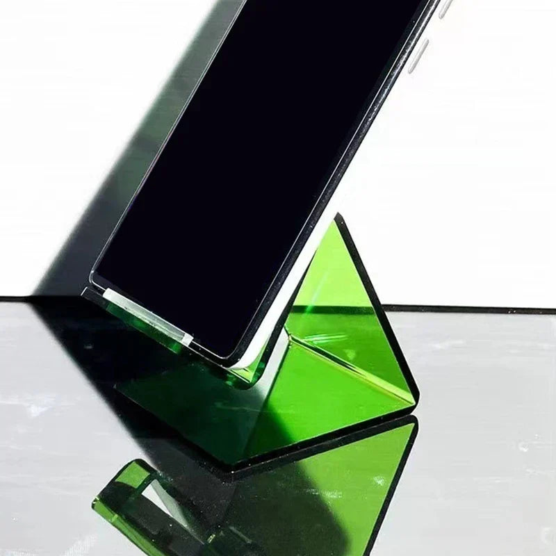 Soporte de escritorio para tableta verde semitransparente que sostiene un teléfono inteligente en posición vertical sobre una superficie oscura reflectante