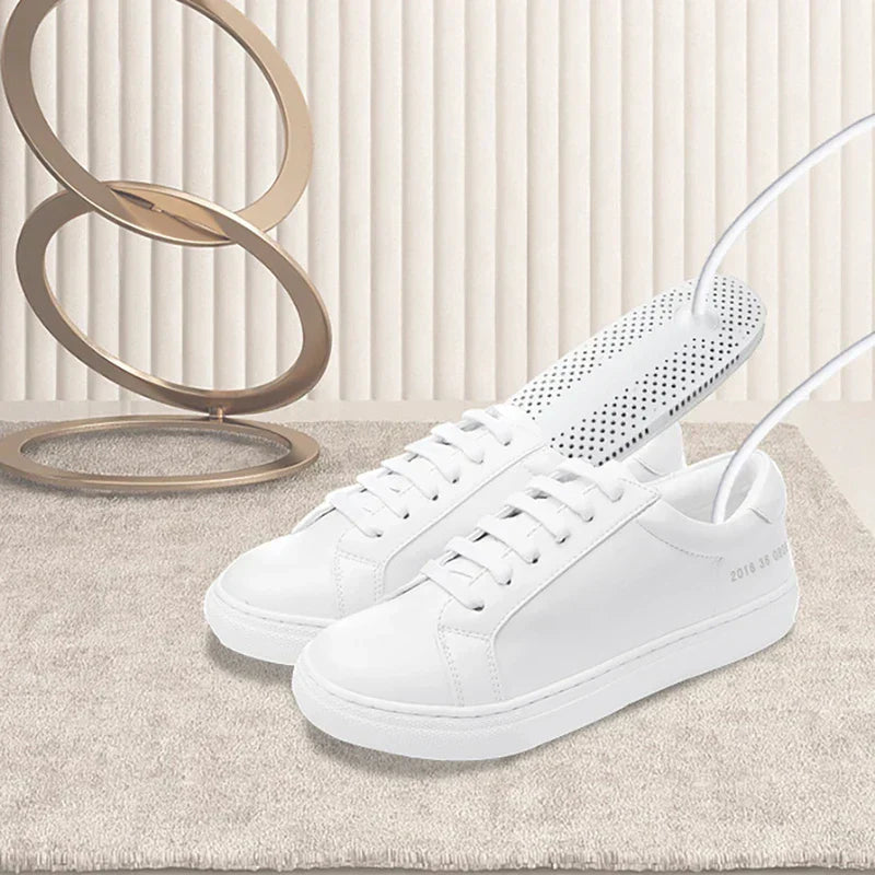 White electric shoe dryer inserted into white sneakers on a carpet