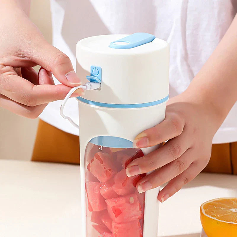 Person plugs a charging cable into a white and blue blender juicer cup with watermelon pieces inside.