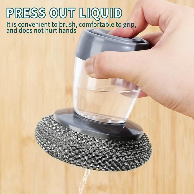 Dish scrubber with handle: hand gripping it, clear liquid dispensing from the mesh scrubbing head