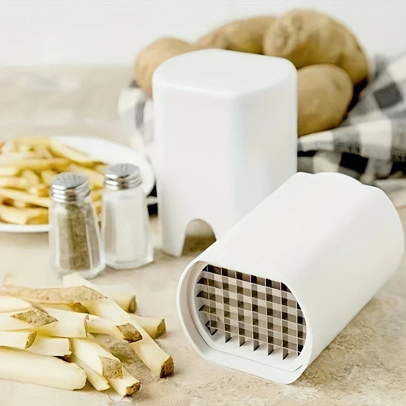 White potato french fry cutter resting on a countertop, with whole potatoes, seasoning shakers, and cut potato strips around it
