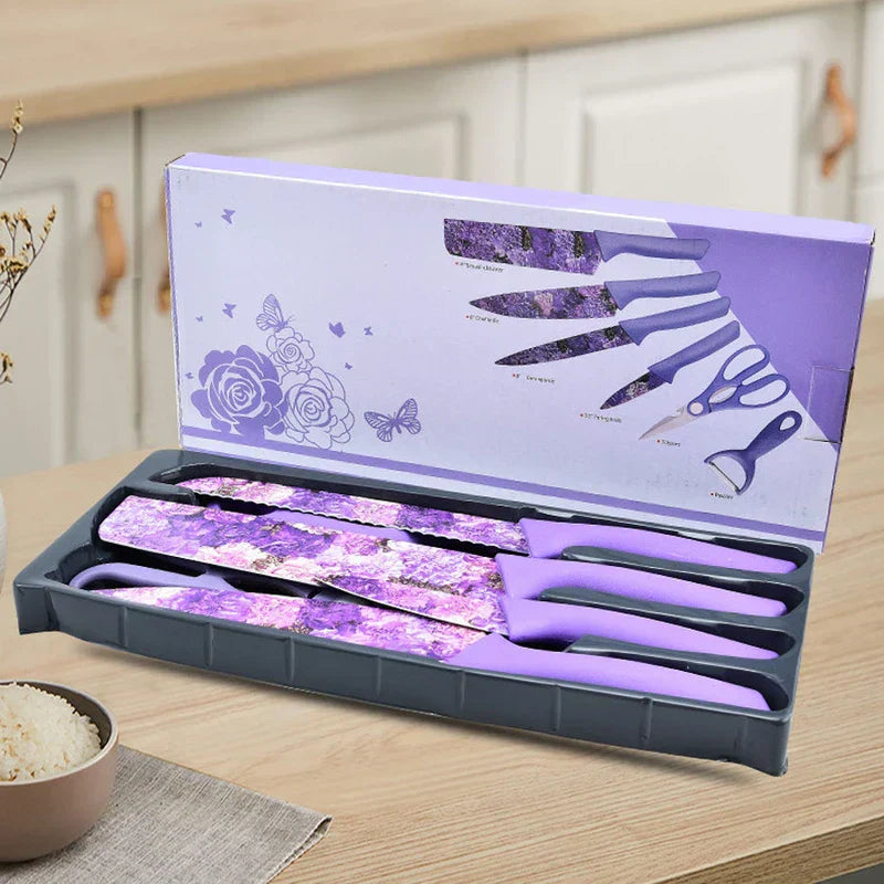 Open box of purple marbled 6 piece kitchen utensil set on wood counter, set includes knives, scissors, peeler