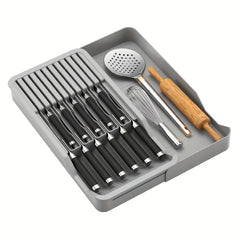 bloque de cuchillos - Organizador gris para cuchillos de cocina lleno de cuchillos con mango negro, un batidor, una espumadera y un rodillo.