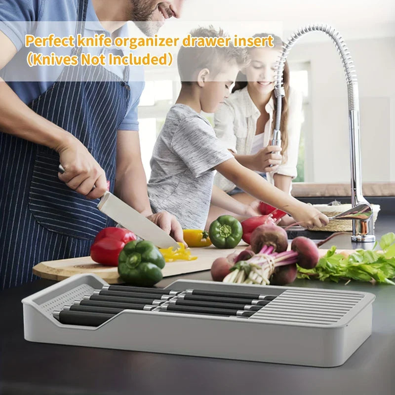 bloque de cuchillos - Familia cocinando en una cocina con un organizador gris para cuchillos que sostiene cuchillos sobre la encimera.