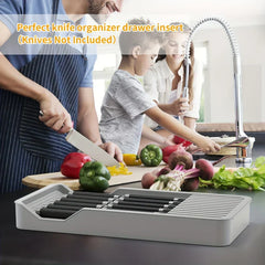 bloque de cuchillos - Familia cocinando en una cocina con un organizador gris para cuchillos que sostiene cuchillos sobre la encimera.