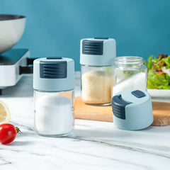 Salt Shaker Bottle - Multiple salt shaker bottles with light blue lids, one with salt inside, set on a marble kitchen counter