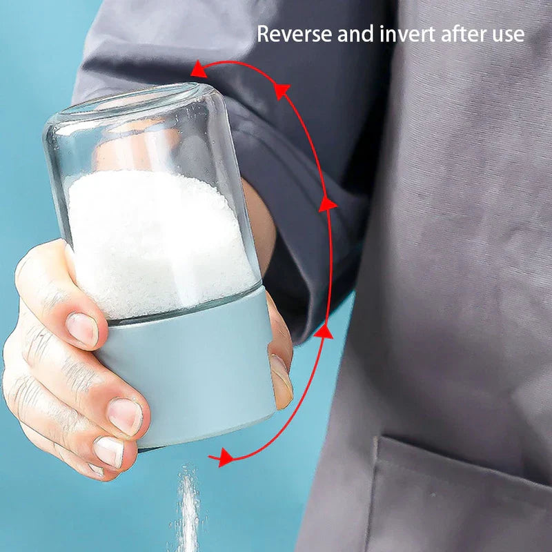 Hand tilting a salt shaker bottle to pour salt, with red arrow showing the inversion direction and text 'Reverse and invert after use'