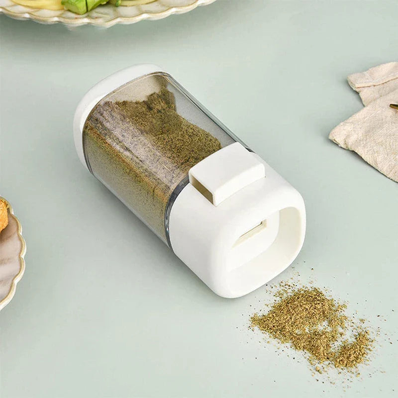 White plastic metered seasoning dispenser with green herb powder on countertop