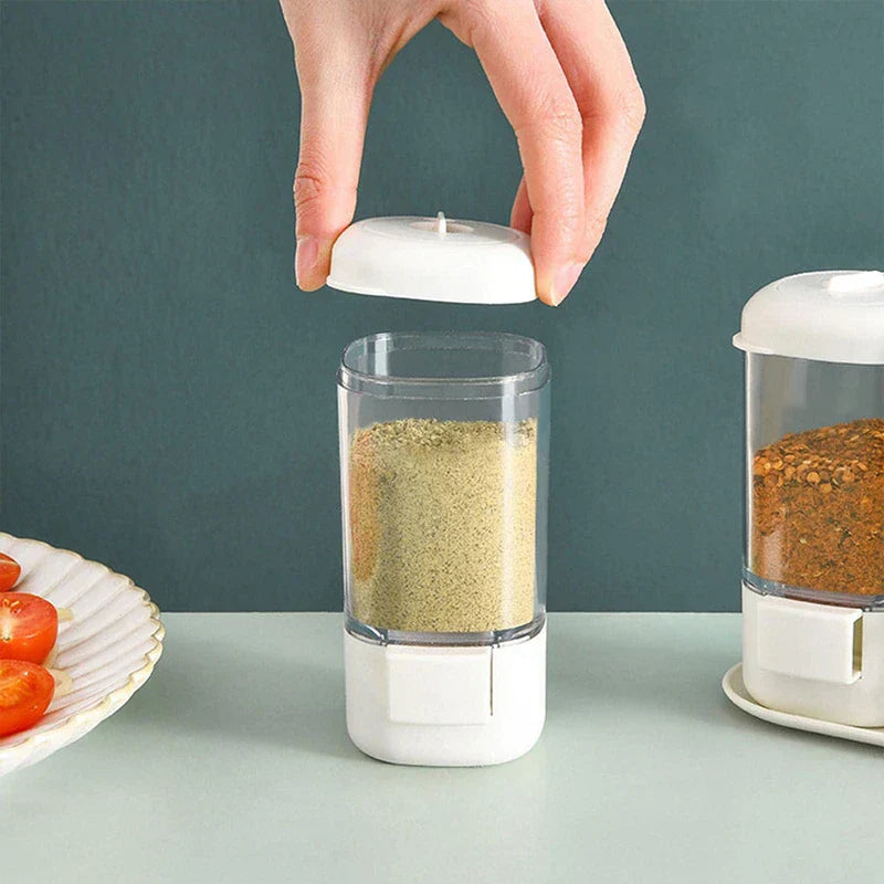 Hand opening lid of clear plastic spice jar with fine seasoning powder inside