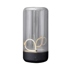 Cylindrical clear glass lamp with dark base, looped internal led light panel, and round control button on a white background.