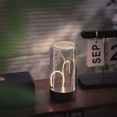Small glass table lamp with curved warm led light panel, dark base, on wooden surface beside a calendar showing SEP.