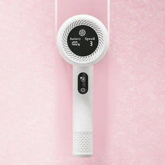Vista frontal de herramienta quitapelusas para ropa blanco de mano con pantalla digital, sobre superficie rosa claro texturizada