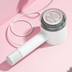 Dispositivo quitapelusas para ropa blanco de mano con cable blanco, sobre fondo rosa angular