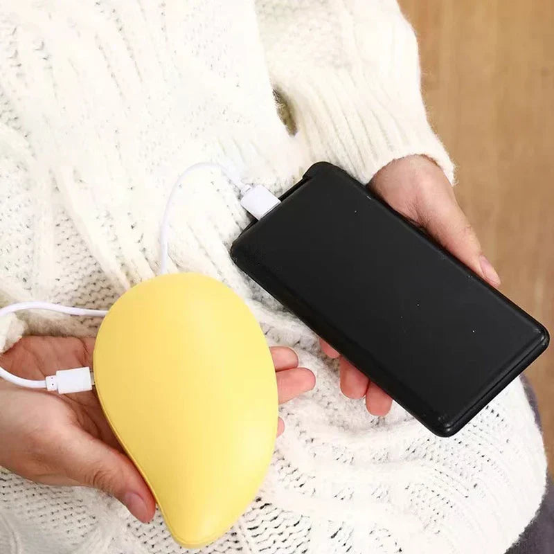 Yellow rechargeable hand warmer held in hand, connected via USB cable to a black power bank