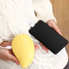 Yellow rechargeable hand warmer held in hand, connected via USB cable to a black power bank