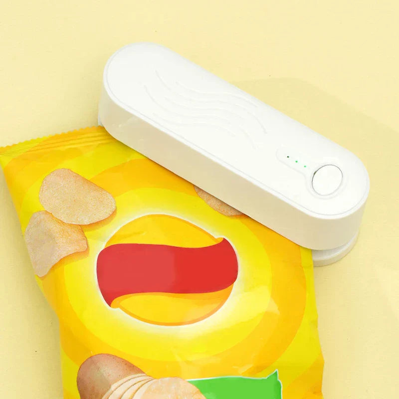 White mini bag heat sealer pressing on an open yellow potato chip bag, with three small green indicator lights visible