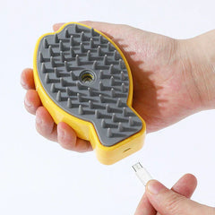 Mano sosteniendo un peine de masaje eléctrico para cuero cabelludo amarillo y gris con cable de carga USB cerca