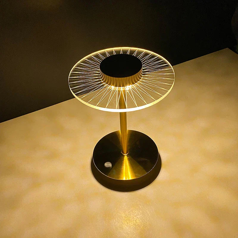 Vista desde arriba de una lámpara de mesa de disco dorada encendida con bombillas led, patrón de luz radial sobre una superficie beige