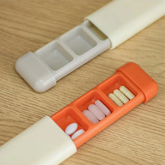 Weekly Pill Organizer - Two opened weekly pill organizers on a wood surface, one with gray compartments and one with orange compartments holding assorted pills