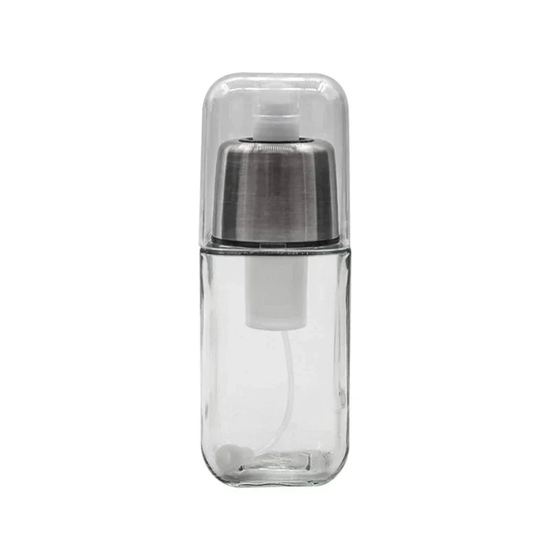 Clear square glass oil sprayer dispenser with silver pump head and transparent dust cap on white background